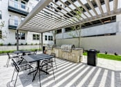 Thumbnail 21 of 46 - A patio with a table and chairs under a pergola.