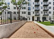 Thumbnail 24 of 46 - A sand pit with red and green balls in front of a building.