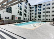Thumbnail 4 of 46 - A swimming pool is located in the middle of a courtyard surrounded by buildings.