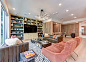 Thumbnail 7 of 46 - A living room with a brown couch, a coffee table, and a chandelier.