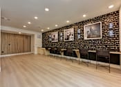 Thumbnail 8 of 46 - A room with a row of chairs and a brick wall with pictures on it.