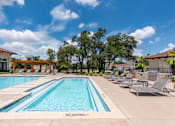 Thumbnail 26 of 59 - a swimming pool with lounge chairs and trees in the background at Avery Ranch, Austin Texas
