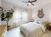 Thumbnail 16 of 21 - A bedroom with a bed, a ceiling fan, and a plant.