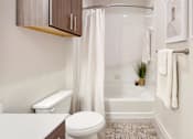 Thumbnail 21 of 21 - A white toilet sits next to a white bathtub in a bathroom.