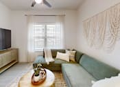 Thumbnail 14 of 21 - A living room with a green couch and a wooden coffee table.