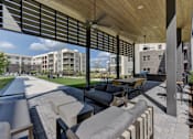 Thumbnail 19 of 103 - Covered outdoor patio with lounge furniture and ceiling fans at Cantarra Apartments, Manor