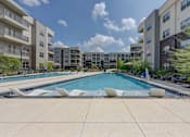 Thumbnail 5 of 103 - Resort style pool with sun shelf and lounge seating at Cantarra Apartments, Manor, TX 78653