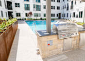 Thumbnail 32 of 46 - A poolside grill is in front of a white building.