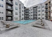 Thumbnail 55 of 140 - Courtyard pool with lounge chairs and modern buildings at Matador Apartments, Austin, Texas