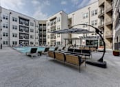 Thumbnail 57 of 140 - Courtyard pool area with lounge furniture and shaded seating at Matador Apartments, Texas