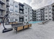 Thumbnail 59 of 140 - Courtyard pool deck with shade canopy and lounge seating at Matador Apartments, Austin, TX 78745