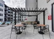 Thumbnail 60 of 140 - Outdoor patio with pergola and poolside dining tables at Matador Apartments, Austin, TX