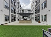 Thumbnail 71 of 140 - Outdoor courtyard with artificial turf and covered kitchen area at Matador Apartments, Texas, 78745