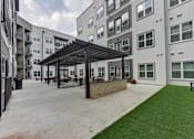 Thumbnail 72 of 140 - Outdoor courtyard with pergola and artificial turf lawn at Matador Apartments, Austin, TX 78745