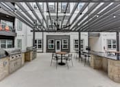 Thumbnail 74 of 140 - Covered outdoor grilling area with dining seating and built in barbecues at Matador Apartments, Austin, Texas