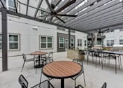 Thumbnail 76 of 140 - Covered outdoor kitchen with bar seating and ceiling fans at Matador Apartments, Texas