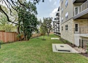 Thumbnail 85 of 140 - Outdoor lawn with cornhole games and apartment balconies at Matador Apartments, Austin, Texas