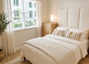 Thumbnail 38 of 46 - A bedroom with a large bed, two lamps, and a window with white curtains.
