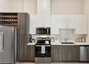 Thumbnail 5 of 44 - a modern kitchen with stainless steel appliances and two tone cabinets with wine racks at Bridge at Windsor Park