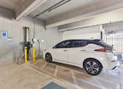 Thumbnail 41 of 44 - a white car is plugged into an electric vehicle charger in the parking garage