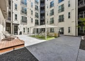Thumbnail 36 of 44 - a turfed courtyard with a trellis, grills, and seating for residents of Bridge at Windsor Park