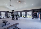Thumbnail 9 of 55 - A spacious gym with a variety of equipment and a ceiling fan.