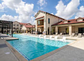 Thumbnail 12 of 55 - A large swimming pool in front of a building with a white fence.