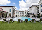 Thumbnail 14 of 55 - A pool surrounded by lawn chairs and buildings in the background.