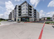 Thumbnail 46 of 51 - A large apartment building with a parking lot in front.