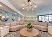 Thumbnail 14 of 51 - A living room with a large sectional sofa, a wooden coffee table, and a chandelier.