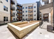 Thumbnail 17 of 51 - A courtyard with a sandpit surrounded by buildings.