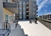Thumbnail 24 of 51 - A modern apartment complex with a spacious courtyard and outdoor seating area.