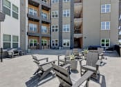 Thumbnail 26 of 51 - A patio area with chairs and tables in front of a building.