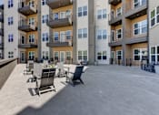 Thumbnail 27 of 51 - A large outdoor patio area with chairs and tables in front of apartment buildings.