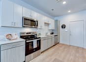 Thumbnail 31 of 51 - A modern kitchen with white cabinets and a wooden floor.