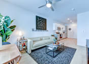 Thumbnail 34 of 51 - A living room with a white couch, a coffee table, and a ceiling fan.