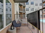 Thumbnail 36 of 51 - A balcony with a black chair and a lantern on a table.