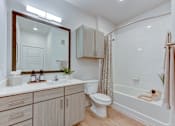 Thumbnail 42 of 51 - A bathroom with a white toilet, a sink with a mirror above it, and a bathtub with a shower curtain.