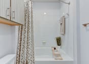Thumbnail 44 of 51 - A white bathroom with a bathtub and a shower curtain.