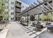 Thumbnail 7 of 51 - A patio with a black metal pergola and grey wicker chairs.