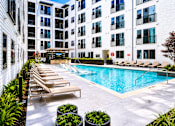 Thumbnail 29 of 46 - A pool surrounded by lounge chairs and potted plants.