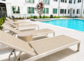 Thumbnail 30 of 46 - A pool with sun loungers in front of a white building.