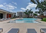 Thumbnail 2 of 51 - A swimming pool surrounded by lounge chairs and trees.