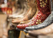 Thumbnail 46 of 46 - A row of cowboy boots with a red one in the front.