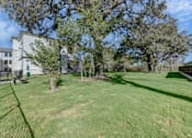 Thumbnail 30 of 80 - A large grassy area with trees and a building in the background.