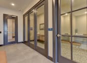 Thumbnail 40 of 80 - A hallway with a glass door and a brown bench.