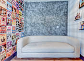 Thumbnail 3 of 80 - A white couch sits in front of a wall covered in posters.