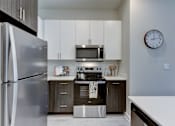 Thumbnail 67 of 80 - A modern kitchen with a stainless steel refrigerator and a microwave above the stove.