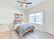 Thumbnail 73 of 80 - A bedroom with a bed, a ceiling fan, and a window with curtains.