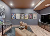 Thumbnail 5 of 80 - A living room with a brown couch, a coffee table, a TV, and a wall with posters.